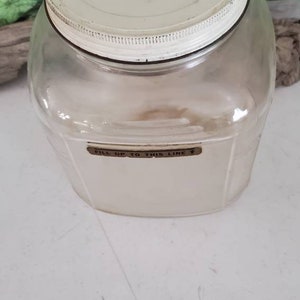 May include: A clear glass jar with a white lid and a brown label that reads "Fill up to this line".