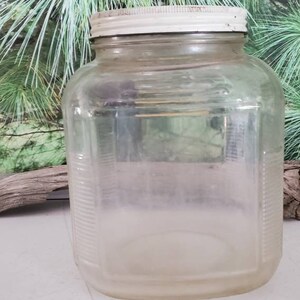 May include: A clear glass jar with a white lid. The jar has a textured surface and is empty.