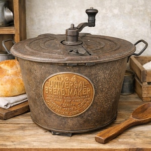 May include: A vintage No. 4 Universal Bread Maker with a dark, weathered metal finish, a top-mounted hand crank, and two side handles. A prominent oval brass plaque on the front displays the text No. 4 UNIVERSAL BREAD MAKER, NEW BRITAIN, CONN. U.S.A.