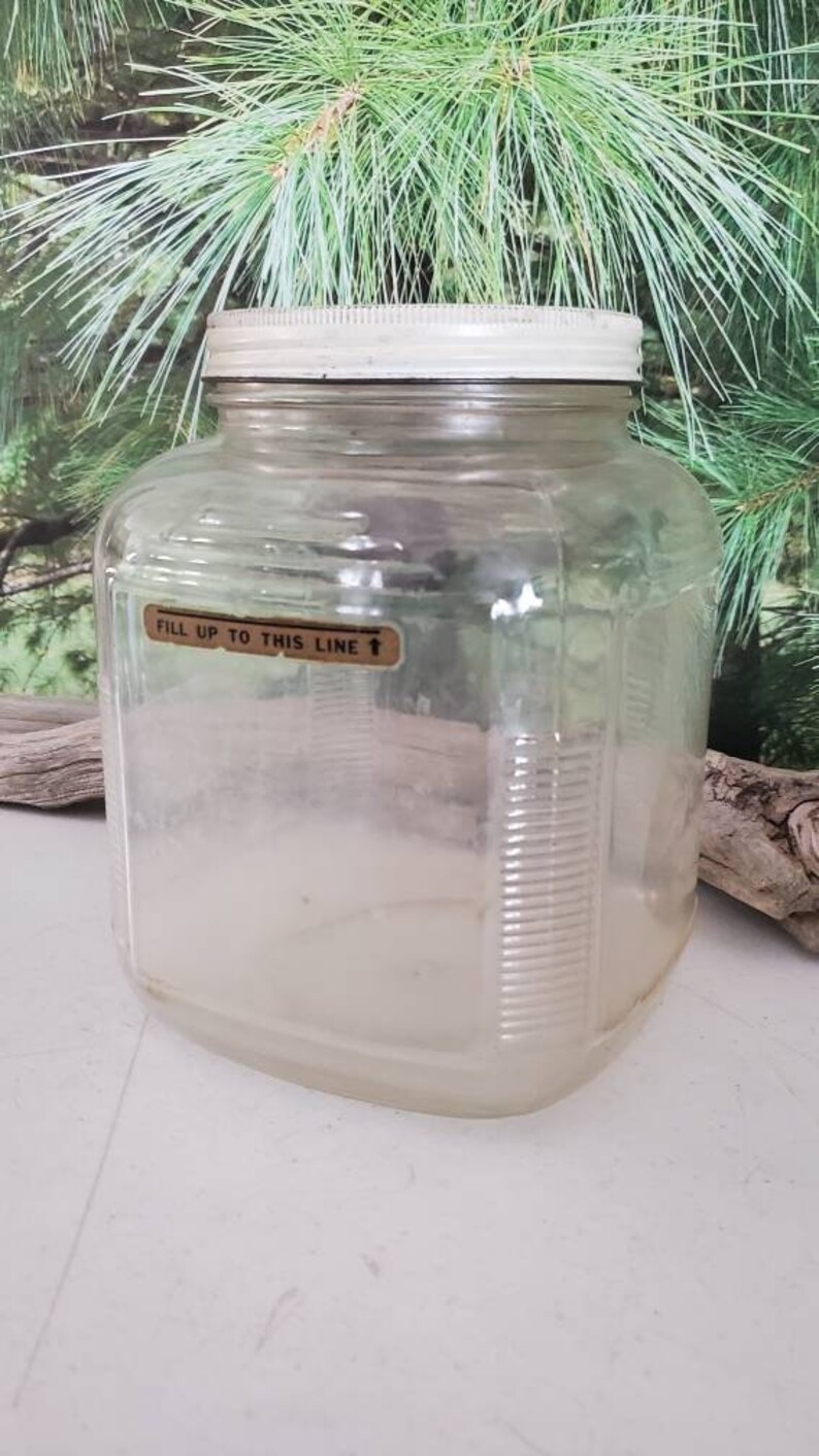 May include: A clear glass jar with a white lid and a label that reads "Fill up to this line".
