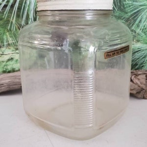 May include: A clear glass jar with a white lid and a label that reads "Fill up to this line".