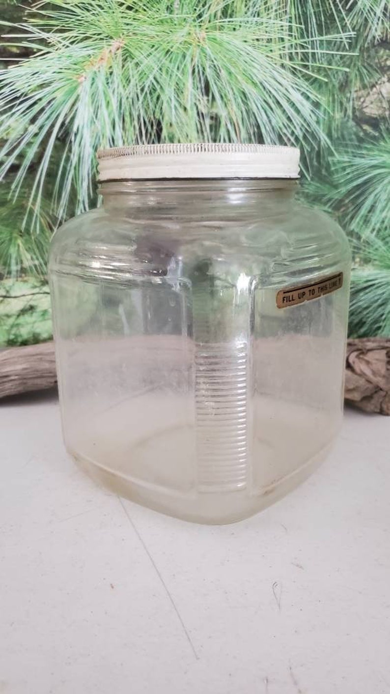 May include: A clear glass jar with a white lid and a label that reads "Fill up to this line".