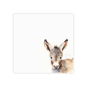 May include: A watercolour painting of a donkey's head and shoulders. The donkey has grey and brown fur, large ears and a white muzzle. The background is white, with a few brown paint splatters.