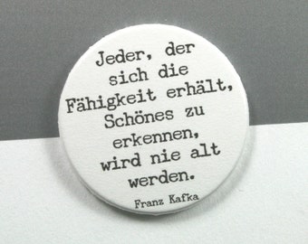 Citazione di Franz Kafka "Chi mantiene la capacità di riconoscere la bellezza non invecchierà mai." // Bottone 38 mm