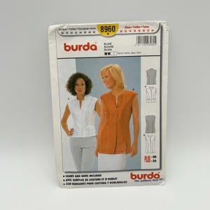 May include: A Burda sewing pattern for a blouse, featuring two women modeling sleeveless blouses. The pattern includes European and US sizes, with the number 8960 prominently displayed. The package also includes the text "SEAMS AND HEMS INCLUDED".