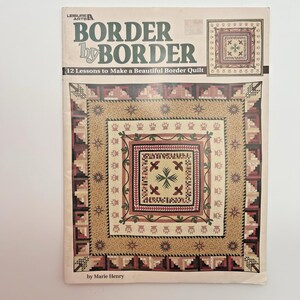 May include: A book cover titled "BORDER by BORDER" by Leisure Arts, featuring a quilt design. The cover displays a detailed quilt pattern in shades of brown, red, and beige, with the text "12 Lessons to Make a Beautiful Border Quilt."