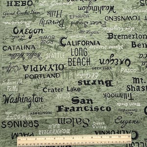 May include: Green fabric with a map-like design featuring place names like Oregon, California, and Washington in black and white. The fabric includes a ruler at the bottom, showing measurements in inches. The fabric is a cotton blend.