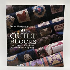 May include: A book cover for "501 Quilt Blocks" by Better Homes and Gardens. The cover features a close-up of various quilt blocks in shades of blue, red, and cream. The title is prominently displayed with the subtitle "A Treasury of Patterns for Patchwork & Appliqué."