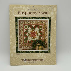 May include: A sewing pattern titled "Raspberry Swirl" by Thimbleberries. The pattern features a quilt design with a central starburst pattern in shades of red, green, and cream. The pattern is 60-inches square.