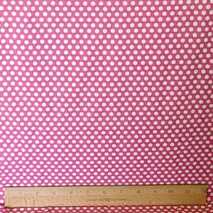 May include: Pink fabric with a white polka dot pattern. The fabric is shown with a ruler for scale.