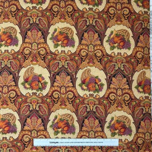 May include: Fabric with a repeating pattern of cornucopias, pumpkins, and grapes in a paisley design. The color palette includes shades of orange, red, gold, and purple. The fabric has a beige background and is suitable for fall-themed projects.