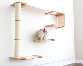 May include: A wall-mounted cat tree with a scratching post, a hammock, and a platform. The cat tree is made of wood and has a natural finish. A cat is sitting on the platform.