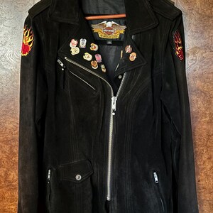 May include: Black suede motorcycle jacket with a zip fastening and multiple patches, including a Harley Davidson logo patch and flame patches on the sleeves.