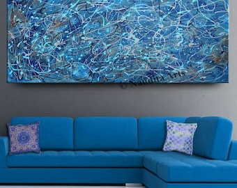 May include: Abstract painting with blue, white, and black paint splatters and lines on a canvas. The painting is hanging on a gray wall above a blue sectional sofa.