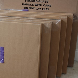 May include: Stack of six cardboard boxes with a label on the top box that reads "FRAGILE-GLASS HANDLE WITH CARE DO NOT LAY FLAT".