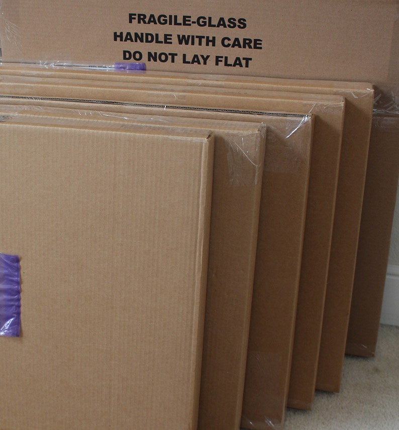 May include: Stack of six cardboard boxes with a label on the top box that reads "FRAGILE-GLASS HANDLE WITH CARE DO NOT LAY FLAT".