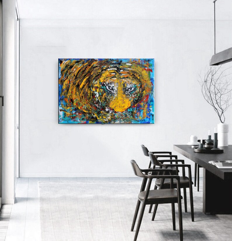 May include: Abstract painting of a lion's face in a swirling mix of yellow, blue, green, and red paint. The lion's eyes are prominent and intense.