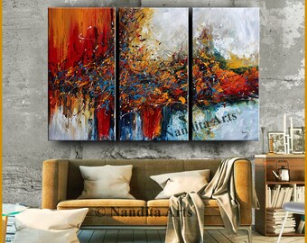 May include: A triptych canvas wall art set featuring an abstract expressionist painting with vibrant splashes of red, orange, yellow, and blue paint. The composition displays thick, textured brushstrokes and energetic splatters across three panels.