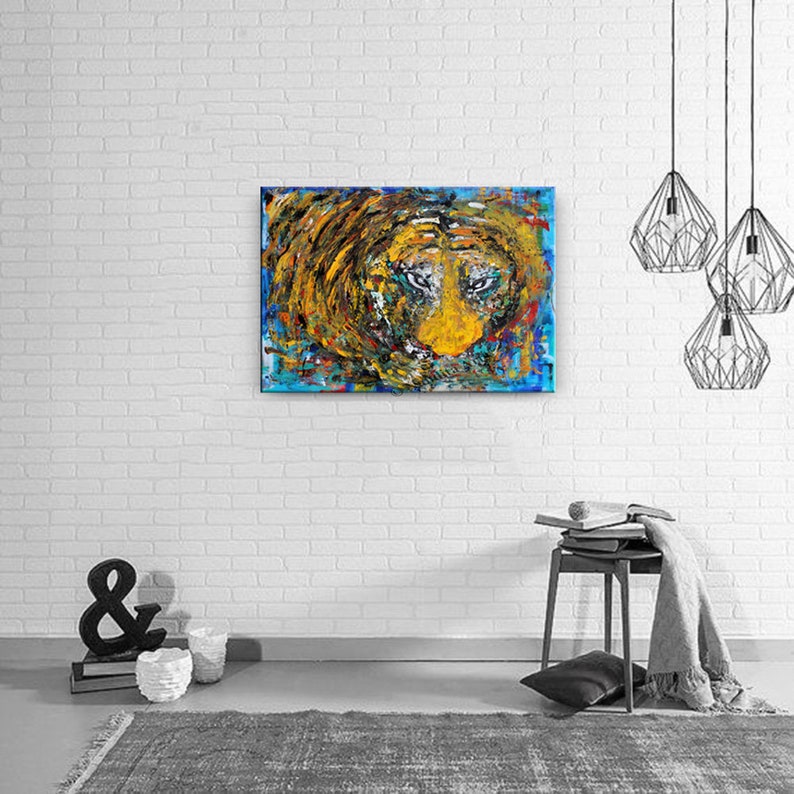 May include: Abstract painting of a tiger's face with blue, yellow, orange, and black paint. The tiger's eyes are a light blue color.