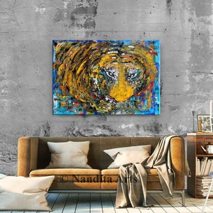 May include: Abstract painting of a lion's face in shades of yellow, blue, and brown. The lion's eyes are prominent and the painting has a textured, brushstroke effect.