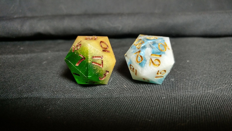 Pu&ograve; includere: Due dadi multicolori con numeri dorati. Un dado &egrave; verde, giallo e bianco con numeri dorati. L'altro dado &egrave; blu, bianco e oro con numeri dorati.