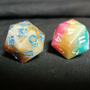 May include: Two multi-colored dice with white numbers. One die is brown and white with blue numbers, the other is a rainbow color with white numbers.