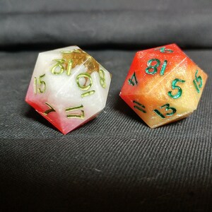 Pu&ograve; includere: Due dadi multicolori con numeri verdi. Un dado &egrave; rosso e bianco con macchie dorate, l'altro &egrave; arancione e giallo con macchie dorate.