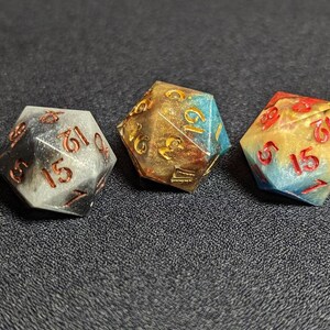 May include: Three multi-colored dice with gold, black, and blue swirls. The dice have numbers 1 through 6 on each side.