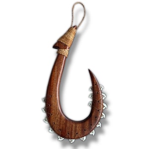 May include: A large, curved wooden hook with a dark brown finish. The hook features a series of small, silver-colored teeth along the inner curve. The top is wrapped with natural-colored twine, and a loop of twine is attached for hanging.