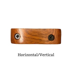 May include: A wooden shelf bracket with two screws. The bracket is stained a light brown color and has a smooth, rounded edge. The text "Horizontal/Vertical" is printed below the bracket.