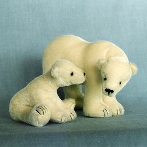 May include: Two white plush polar bear stuffed animals. The larger bear is standing with its head bent down, looking at the smaller bear. The smaller bear is sitting with its head turned to look at the larger bear.