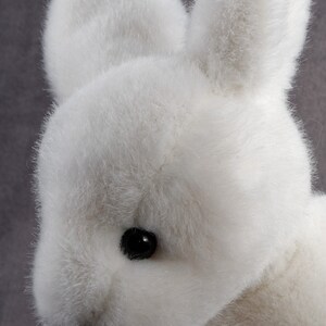 May include: A white plush bunny with black eyes. The bunny is soft and cuddly.