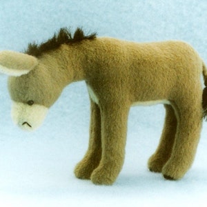 Pode incluir: Um brinquedo de peluche de burro marrom com crina e cauda pretas. O burro tem uma expressão triste e olha para baixo.