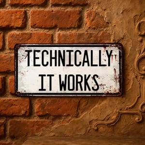 Op de afbeelding: Een rechthoekig metalen bord met de woorden "TECHNICALLY IT WORKS" in zwarte letters. Het bord heeft een witte achtergrond met roestachtige markeringen en een donkerbruine rand. Het bord is op een bakstenen muur gemonteerd.