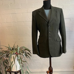 May include: A dark green blazer with a single-breasted closure and four buttons. The blazer has a notched lapel and flap pockets.