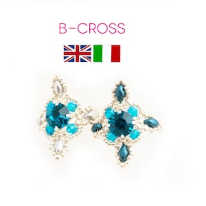 Può includere: Un paio di orecchini blu e argento con un design a croce. Gli orecchini presentano un grande cristallo blu al centro e cristalli blu più piccoli che lo circondano.