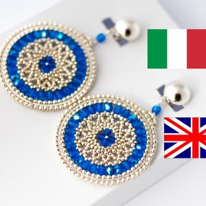 May include: A pair of silver and blue beaded earrings with a circular design. The earrings are hanging from silver hooks.