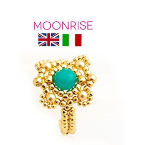 Può includere: Anello in oro con una pietra turchese circondata da perline dorate. L'anello è regolabile e ha un design delicato.