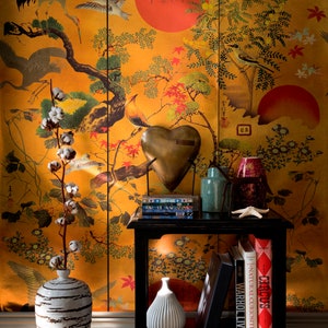 May include: A black end table with a gold heart-shaped sculpture, two vases, and a stack of books. The table is in front of a wall with a Japanese-style wallpaper featuring birds, flowers, and a red sun.