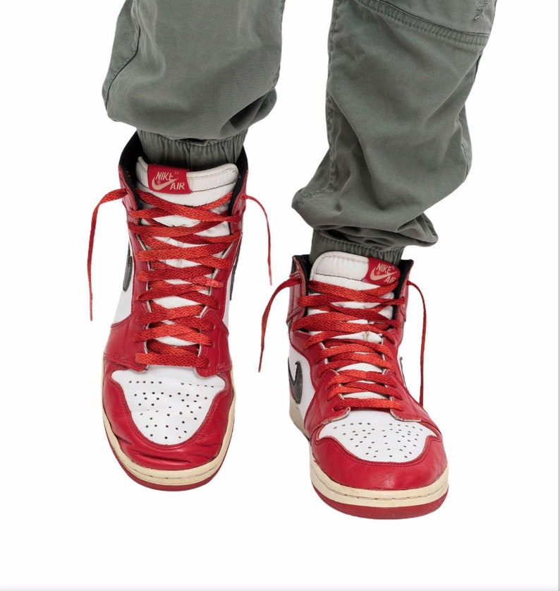 May include: A pair of red and white high-top sneakers with black Nike Air branding on the side and tongue. The laces are red and the shoes are worn.