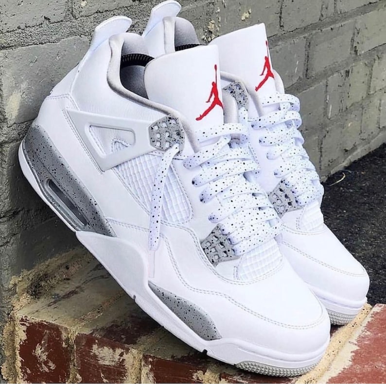 Puede incluir: Zapatillas blancas de cuero con detalles grises moteados y logotipo Jumpman rojo. Los cordones son blancos con motas grises.