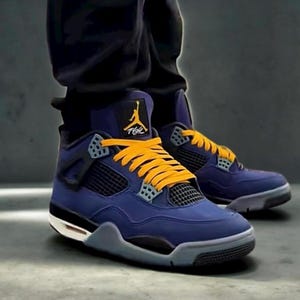 May include: A pair of blue and black high-top sneakers with yellow laces. The sneakers have a gray sole and a black mesh panel. The iconic Jumpman logo is visible on the tongue.