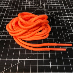 Puede incluir: Un cord&oacute;n de zapato de color naranja brillante, enrollado y listo para usar. El cord&oacute;n est&aacute; hecho de un material duradero y trenzado.
