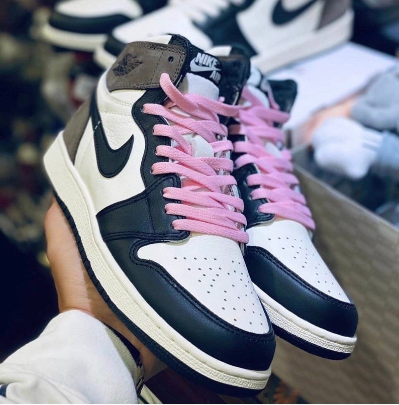 May include: A pair of black and white high-top sneakers with pink laces. The sneakers have a suede toe and a Nike Air logo on the side.