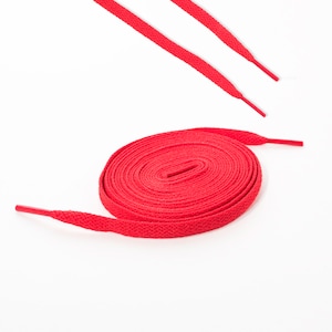 May include: A red shoelace is coiled up on a white surface. The shoelace is about 100 cm long.