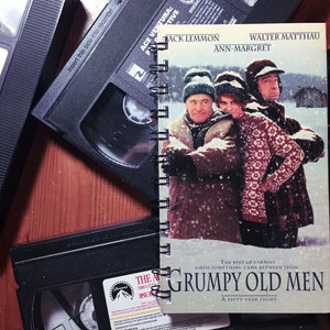 May include: A vintage VHS tape case for the movie "Grumpy Old Men" starring Jack Lemmon, Walter Matthau, and Ann-Margret. The case is white with a snowy scene of the three actors on the front.