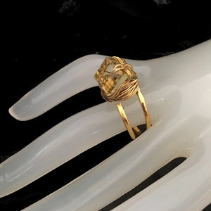 May include: A gold wire wrapped ring with a large, faceted, yellow gemstone.