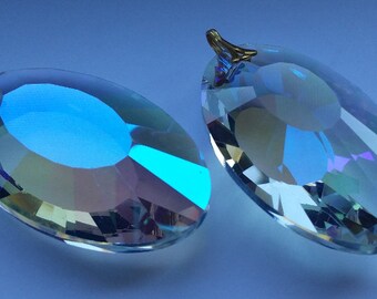 May include: Two iridescent crystal prisms with a gold metal hanging loop. The prisms are oval shaped and have a rainbow effect.
