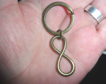 May include: A gold-toned infinity symbol keychain with a round key ring.
