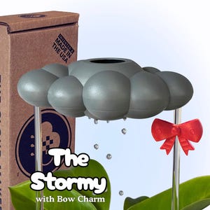 May include: A gray cloud-shaped decorative item with clear stems and a red bow charm. The text "The Stormy with Bow Charm" is displayed on the image. The product is packaged in a brown box with text that reads "Invented & Made in the USA".